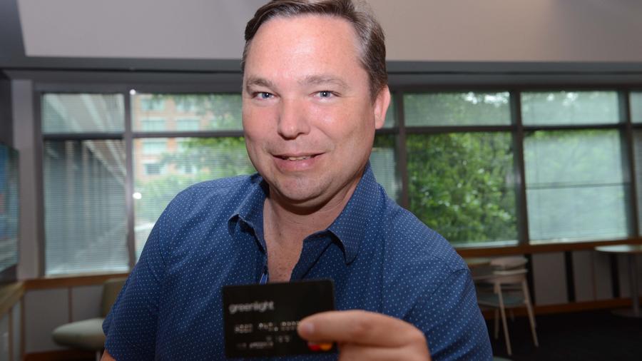 Photo of Tim Sheehan, Founder of Greenlight, standing in the ATDC office showing one of Greenlight's debit cards. Photo was taken by AJC